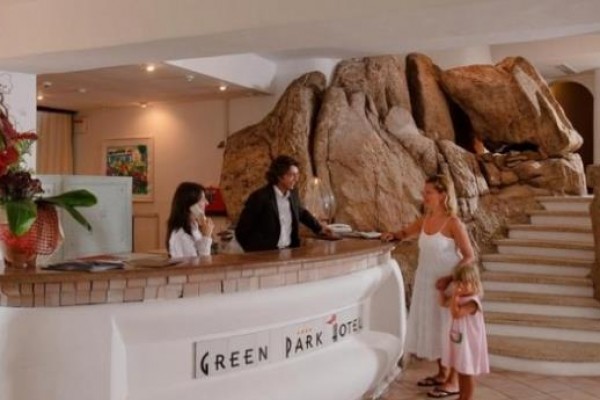Recepce hotelu s přírodní kamennou dekorací a dvěma hosty.