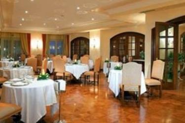 Elegantní restaurace s kulatými stoly a židlemi uprostřed místnosti.