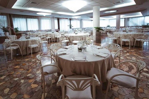 Elegantní restaurace s kulatými stoly pokrytými bílými ubrusy.