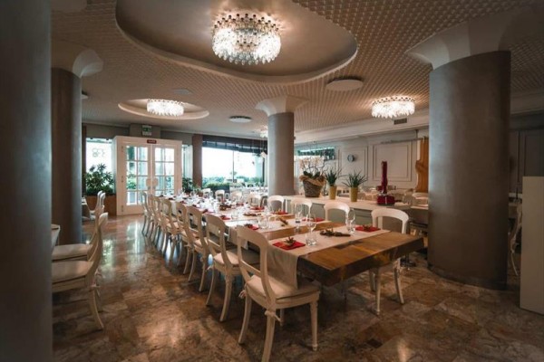 Prostorná a elegantně zařízená jídelna s dlouhými stoly a křišťálovými lustry.