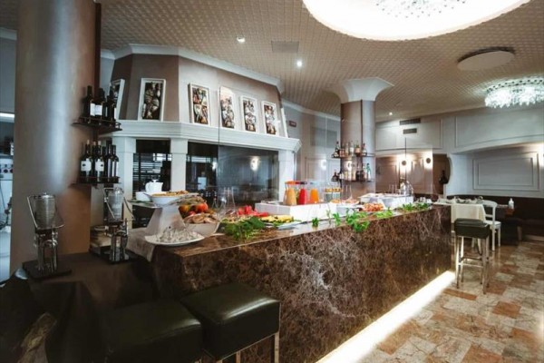 Restaurace s mramorovým bufetovým pultem a vystavenými nápoji a jídlem.  