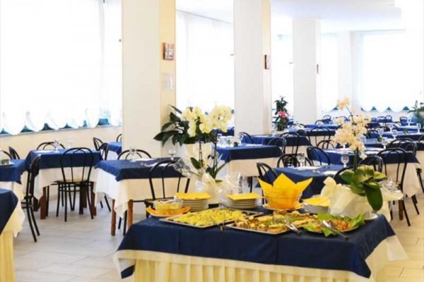 Restaurace s prostřenými stoly pokrytými modrobílými ubrusy a kyticí na stole.