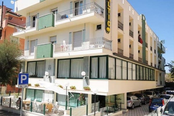 Plážový hotel se čtyřmi podlažími a parkovištěm na rohu ulice.
