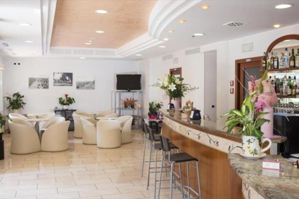 Elegantní hotelový bar s bílými křesly a květinovou výzdobou.