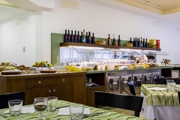 Samoobslužný bufet s nabídkou nápojů a jídla v restauraci s prostřenými stoly.