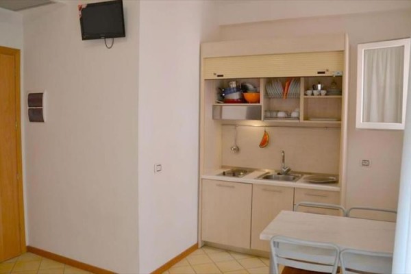 Malá kuchyňská linka s dřezem, stolem a židlemi v rohu místnosti.