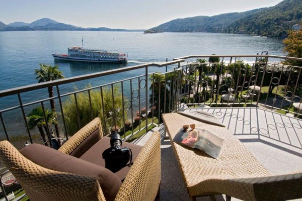 Výhled z balkonu na jezero s projíždějící lodí a okolními kopci.