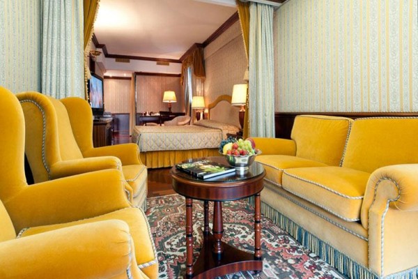 Elegantní obývací pokoj s žlutou sedací soupravou a přilehlou ložnicí.