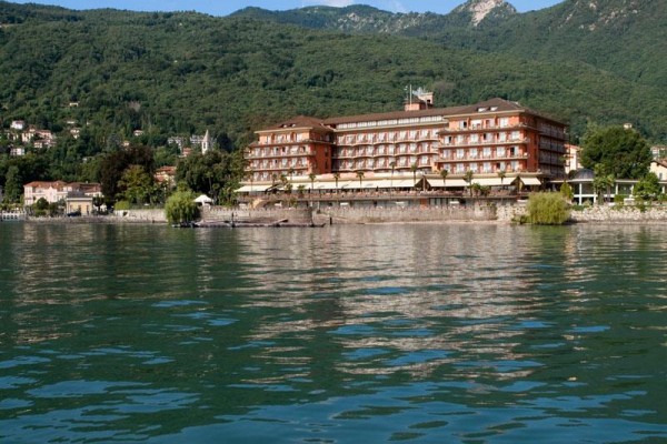 Velký hotel na břehu jezera s kopci v pozadí.