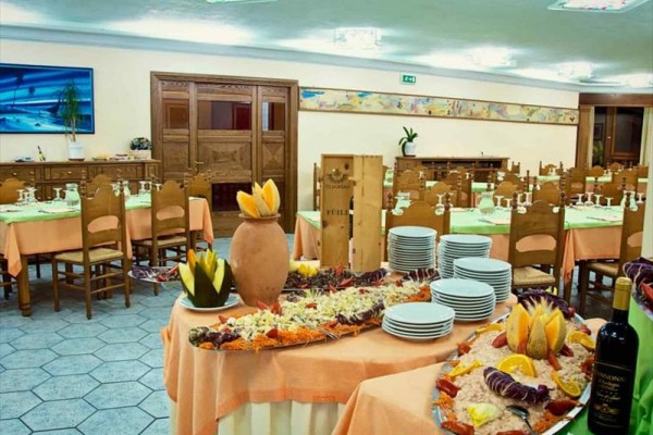 Restaurace s připravenými stoly a bufetovými pokrmy na stole uprostřed.