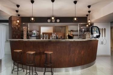 Moderní bar s dřevěným pultem, židlemi a závěsnými svítidly.