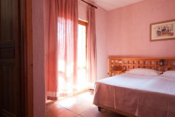 Ložnice s dvoulůžkem, růžovými stěnami a závěsy vedle koupelny.