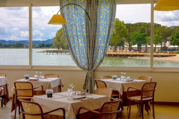 Restaurace s výhledem na jezero a pobřeží přes velká okna.