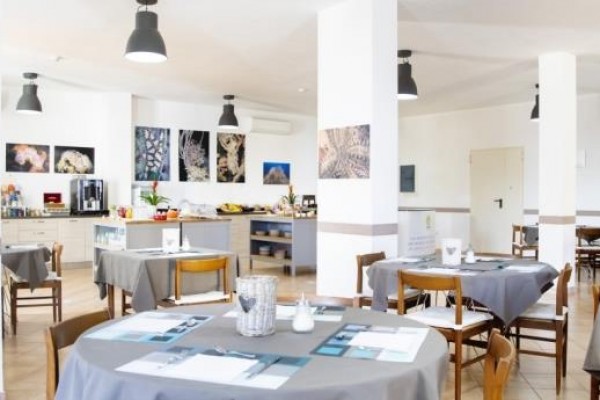 Prosvětlená restaurace s několika stolky a moderní výzdobou.