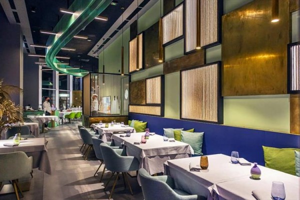 Moderní restaurace s elegantním uspořádáním stolů a barevným interiérem.  