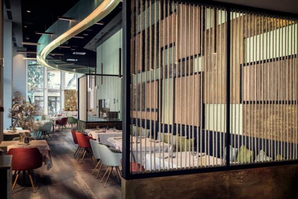 Moderní restaurace s dřevěnými oddělovacími panely a barevnými židlemi.