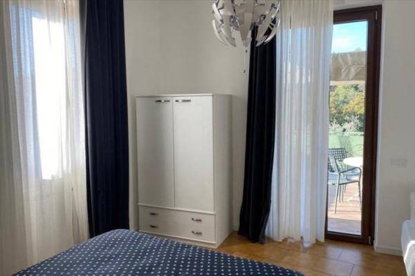 Ložnice s postelí, skříní a dveřmi vedoucími na balkon.
