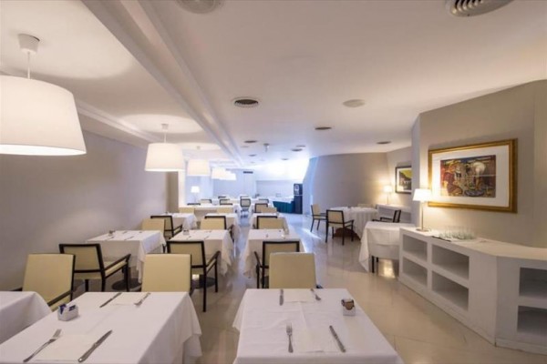 Elegantní restaurace s bílými ubrusy a moderním osvětlením.