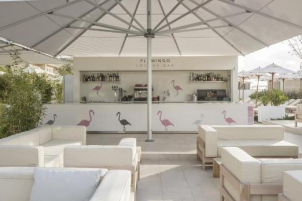 Venkovní lounge bar s bílými pohovkami a velkými slunečníky.