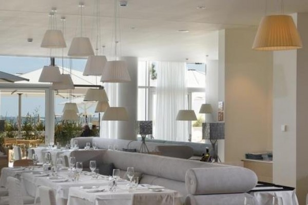 Elegantní restaurace s bílými ubrusy a velkými lampami.