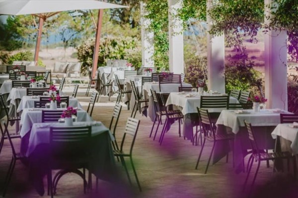 Venkovní terasa restaurace s elegantně prostřenými stoly a židlemi.