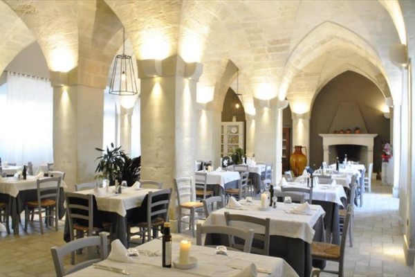 Středověká restaurace s klenutými stropy a prostřenými stoly.