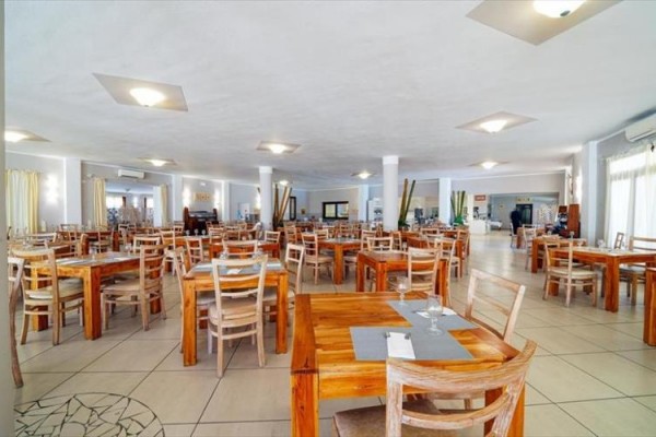 Prostorná restaurace s dřevěnými stoly a židlemi ve světlém interiéru.