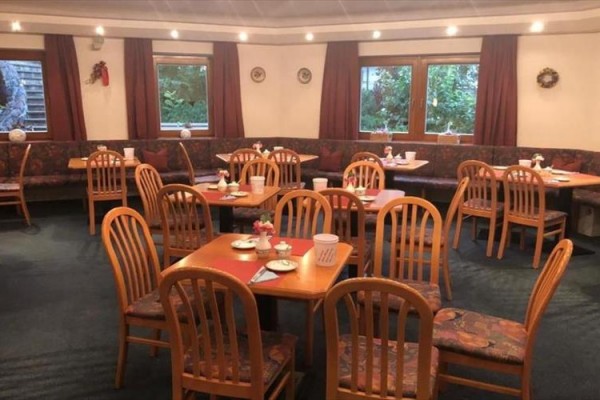 Restaurace s dřevěnými stoly a židlemi, nachystaná na hosty.