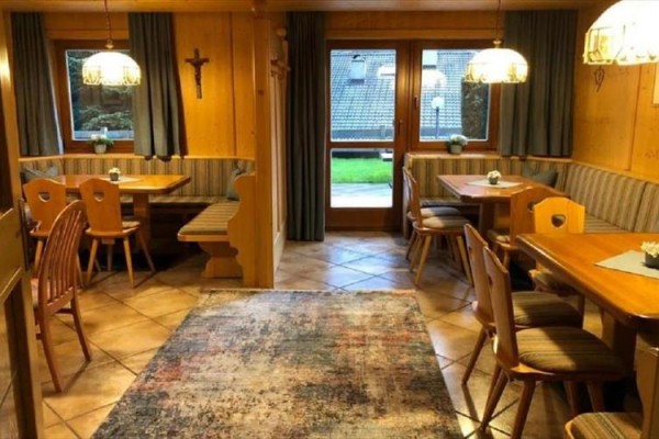 Restaurace se dřevěným obložením, lavicemi a jídelními stoly.