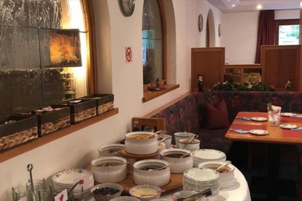 Jídelní stůl v restauraci s různými nádobami a talíři připravenými k servírování jídla.