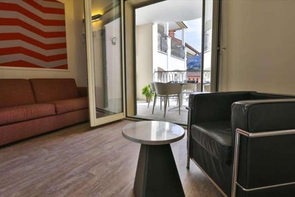 Moderní obývací prostor s otevřenými dveřmi na balkon s výhledem na hory.