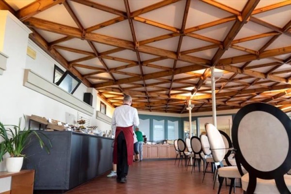 Elegantní interiér restaurace s dřevěným stropem a kulatými židlemi.