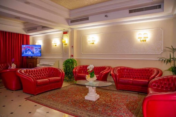 Elegantní lobby s červenými koženými sedačkami, konferenčním stolem a televizí.