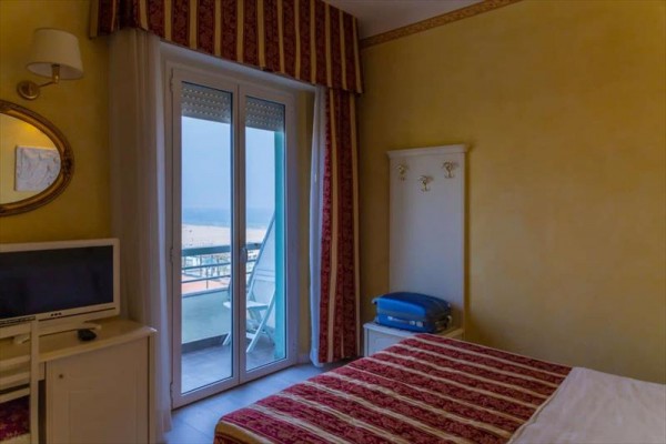 Pokoj s postelí a výhledem na balkon s mořem.