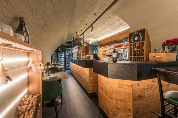 Moderní interiér restaurace s dřevěným barem a stoly.