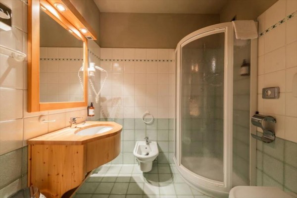 Elegantní koupelna s dřevěným umyvadlem, sprchovým koutem a bidetem.