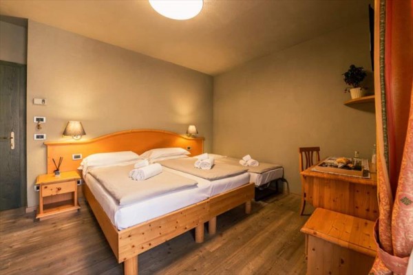 Dvojlůžkový pokoj s dřevěným nábytkem a lampami na nočních stolcích.