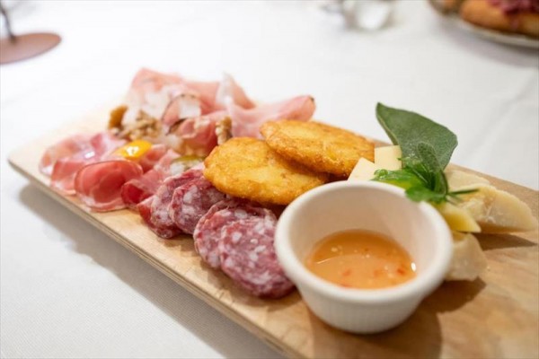 Talíř antipasti s různými druhy masa, sýrem a omáčkou.
