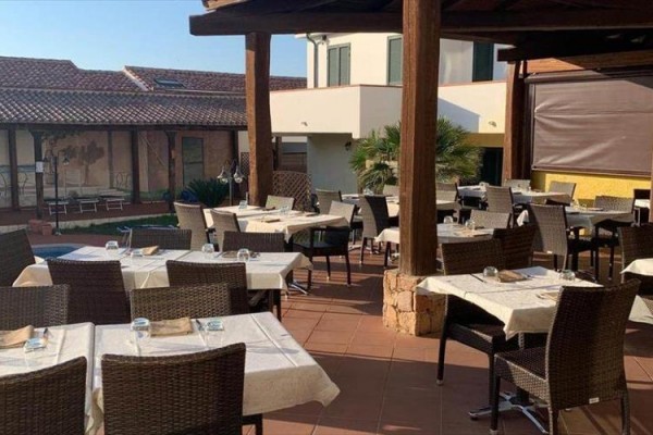 Venkovní terasa restaurace s prostřenými stoly a židlemi.