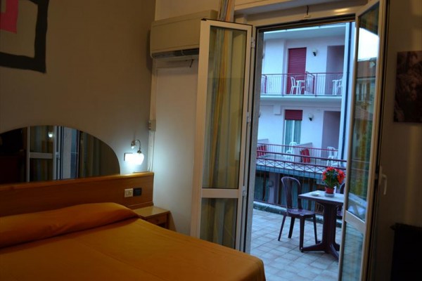 Ložnice s výstupem na balkon s výhledem na protější budovu.
