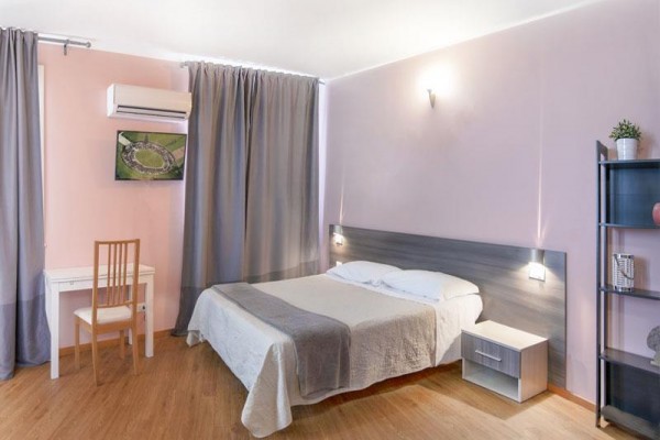 Ložnice s manželskou postelí, nočním stolkem, pracovním stolem a klimatizací.
