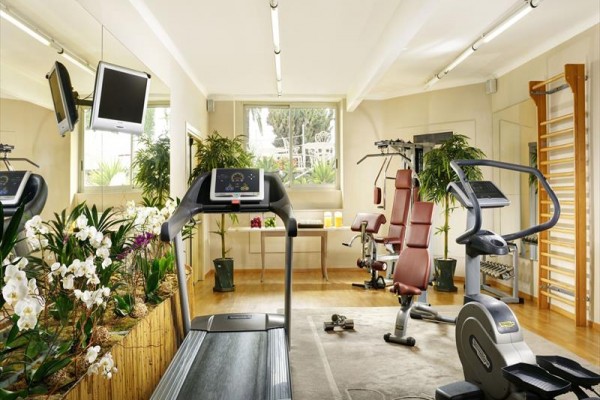 Moderní fitness centrum s cvičebními stroji a zrcadlem.