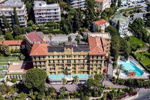 Budova hotelu s bazénem a okolními stromy z ptačí perspektivy.