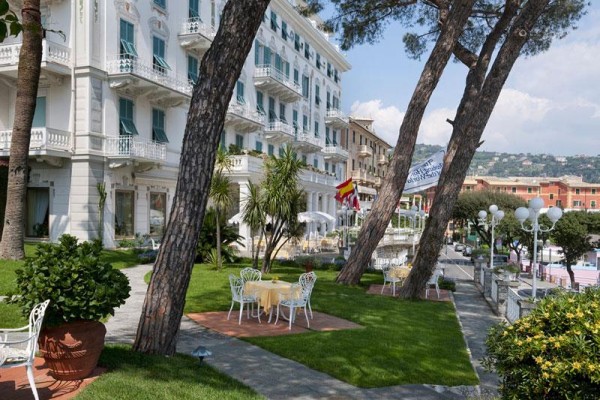 Elegantní hotel s terasou a zahradou s posezením pod stromy.