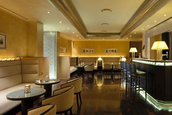 Elegantní hotelový bar s pohodlnými křesly a osvětleným pultem.