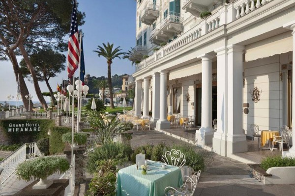 Venkovní terasa Grand Hotelu Miramare s výhledem na moře, ozdobená zelení a americkou vlajkou.