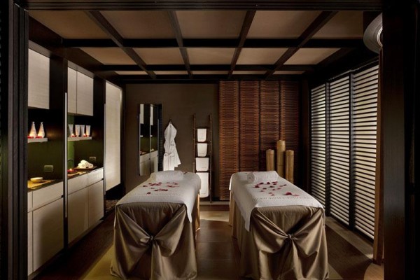 Dvě masážní lehátka v luxusní spa místnosti s jemným osvětlením a dekorem.  