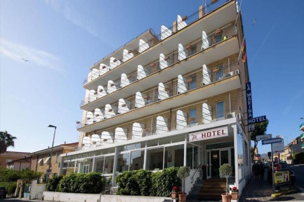 Čtyřpatrový hotel s balkony a vstupem z ulice.