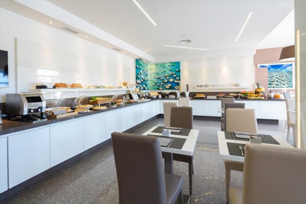 Moderní restaurace s bufetovým stolem a uměleckou výzdobou na stěně.