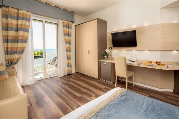 Moderní hotelový pokoj s výhledem na moře a balkonem.